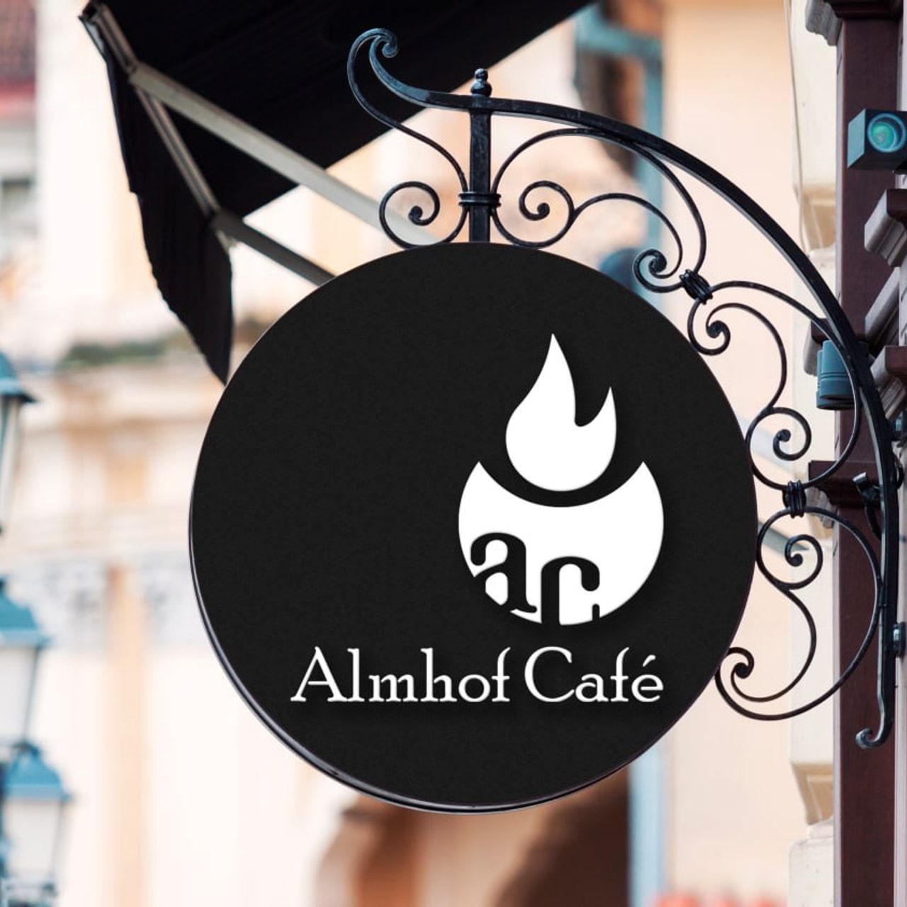Круглая вывеска Almhof Café с чёрным знаком на кованых кронштейнах