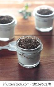 yoghurt with nuts and grated chocolate in small glass jars on a wooden background