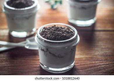 yoghurt with nuts and grated chocolate in small glass jars on a wooden background