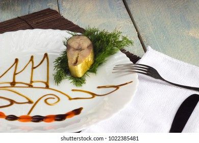 a piece of mackerel on a white dish with a pattern of soy sauce on a wooden background