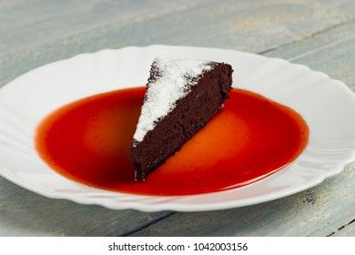 Chocolate decadence pie with strawberry jam on a wooden background