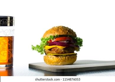 hamburger with cheese, onions, cucumbers and a glass with a drink
