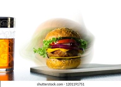 hamburger with cheese, onions, cucumbers and a glass with a drink