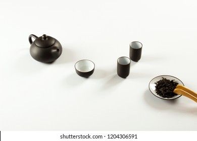small clay teapot, tea and tea ceremony supplies on a white background
