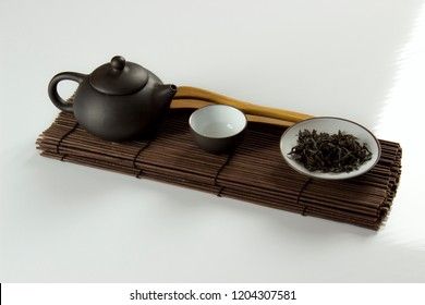small clay teapot, tea and tea ceremony supplies on a white background
