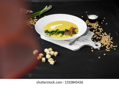 Pea soup with pieces of bacon, parsley and onion in a bowl on a dark background. Pea cream soup. with a curtain