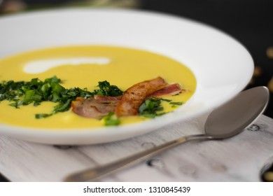 Pea soup with pieces of bacon, parsley and onion in a bowl on a dark background. Pea cream soup. Macro