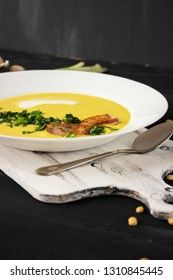 Pea soup with pieces of bacon, parsley and onion in a bowl on a dark background. Pea cream soup.