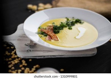 Pea soup with pieces of bacon, parsley and onion in a bowl on a dark background. Pea cream soup. macro focus shading