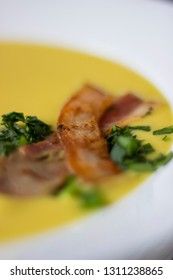 Macro pea soup with pieces of bacon, parsley and onion in a bowl on a dark background. Pea cream soup.
