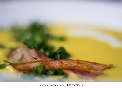 Pea soup with pieces of bacon, parsley and onion in a bowl on a dark background. Pea cream soup. Macro.