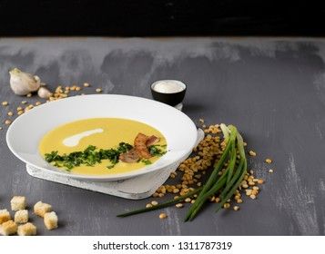 Pea soup with pieces of bacon, parsley and onion in a bowl on a dark background. Pea cream soup.