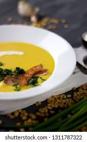 Pea soup with pieces of bacon, parsley and onion in a bowl on a dark background. Pea cream soup.