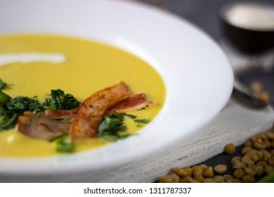 Macro pea soup with pieces of bacon, parsley and onion in a bowl on a dark background. Pea cream soup.