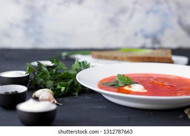 Traditional Ukrainian Russian borsch with sour cream and white beans on a dark background. Red vegetable beetroot soup.