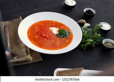 Traditional Ukrainian Russian borsch with sour cream and white beans on a dark background. Red vegetable beetroot soup. Outside observer.