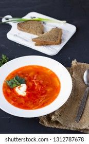 Traditional Ukrainian Russian borsch with sour cream and white beans on a dark background. Red vegetable beetroot soup.