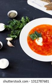 Traditional Ukrainian Russian borsch with sour cream and white beans on a dark background. Red vegetable beetroot soup.