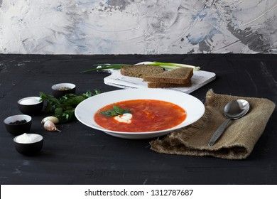 Traditional Ukrainian Russian borsch with sour cream and white beans on a dark background. Red vegetable beetroot soup.