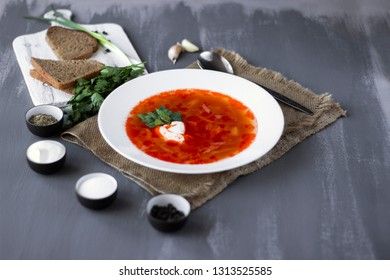 Traditional Ukrainian Russian borsch with sour cream and white beans on a dark background. Red vegetable beetroot soup.