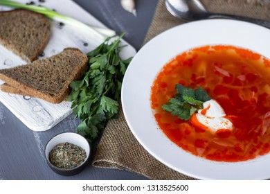 Traditional Ukrainian Russian borsch with sour cream and white beans on a dark background. Red vegetable beetroot soup.