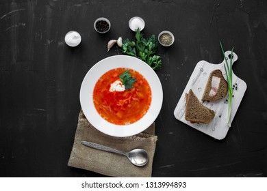 Traditional Ukrainian Russian borsch with sour cream and white beans on a dark background, view from above. Red vegetable beetroot soup.