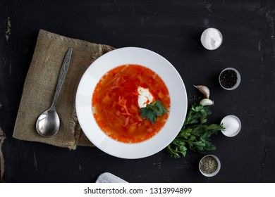 Traditional Ukrainian Russian borsch with sour cream and white beans on a dark background, view from above. Red vegetable beetroot soup.