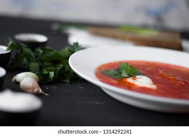 Traditional Ukrainian Russian borsch with sour cream and white beans on a dark background. Red vegetable beetroot soup.