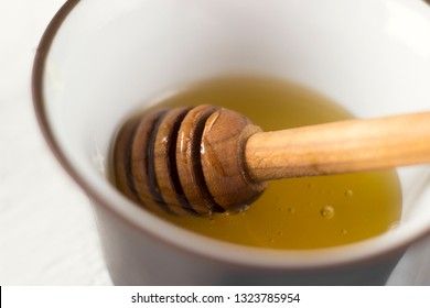 Honey spoon and fragrant honey in a bowl, macro
