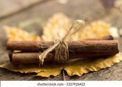 Cinnamon sticks tied with string on wooden background, close up