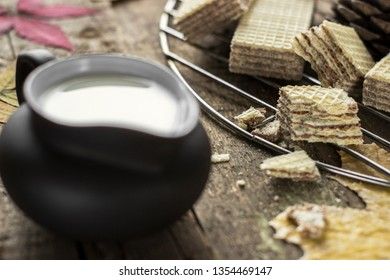 Sweet russian artek waffles on wooden background, with a pot of milk. Traditional sweets and dessert.