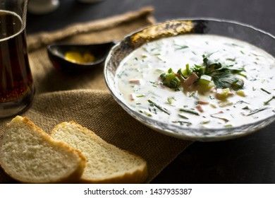 Cold Soup Okroshka. With sausage, vegetables and kvass serving size in bowl and raw ingredients on wooden table