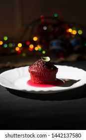 Red cupcake with chocolate chips on a dark background with multi-colored bokeh