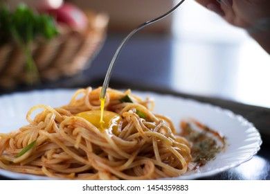 Delicious pasta with egg yolk, on wooden table.