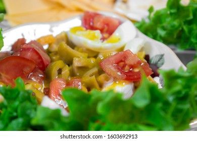 Greek salad with olives, tomatoes, feta cheese, onions in blue bowl on wooden background. Close up. Selective focus.