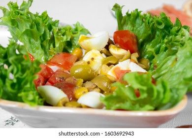 Greek salad with olives, tomatoes, feta cheese, onions in blue bowl on wooden background. Close up. Selective focus.