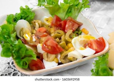 Greek salad with olives, tomatoes, feta cheese, onions in blue bowl on wooden background. Close up. Selective focus.