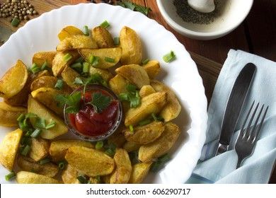 Country style fried potatoes with onions and ketchup. Fried potatoes in large slices.
