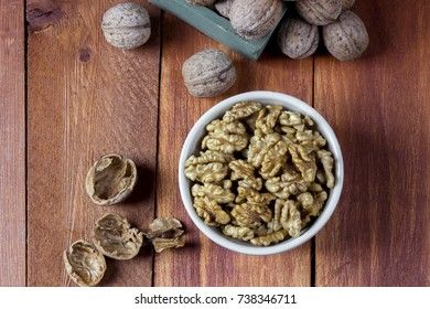 Peeled walnut in a white cup on a wooden background